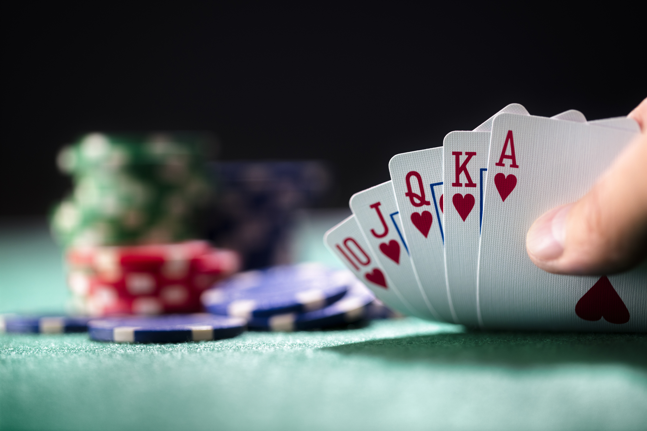 Playing poker in a Las Vegas, NV casino holding winning royal flush hand of cards.